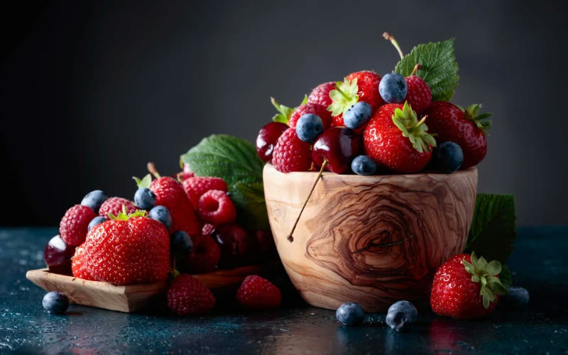 Fresas, arándanos y frambuesas en un cuenco de madera